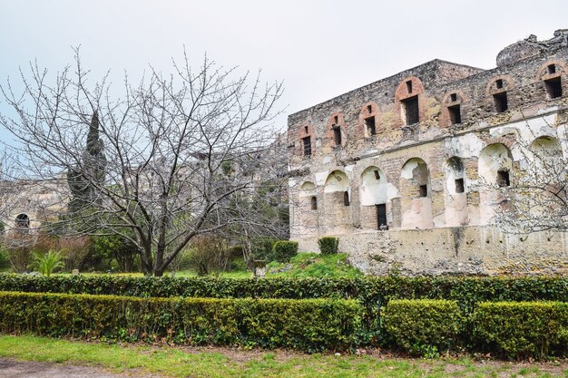 Bild einer Ruine mit Hecken im Vordergrund unter bewölktem Himmel