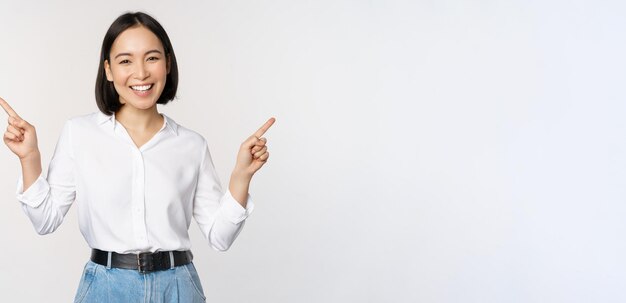 Bild einer schönen asiatischen Frau, die mit dem Finger nach links und rechts zeigt und Entscheidungen trifft, die zwei Varianten zeigen, die über weißem Hintergrund stehen