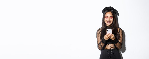 Bild einer schönen asiatischen Frau im gotischen Spitzenkleid, die sich als Hexe auf der Halloween-Party ausgibt