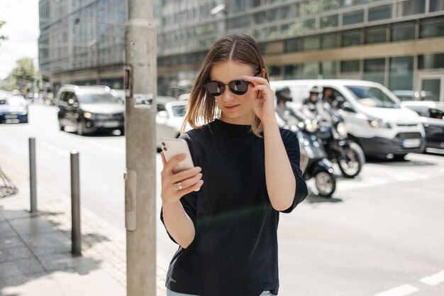 Bild einer süßen jungen Frau, die mit Sonnenbrille am Telefon lächelt