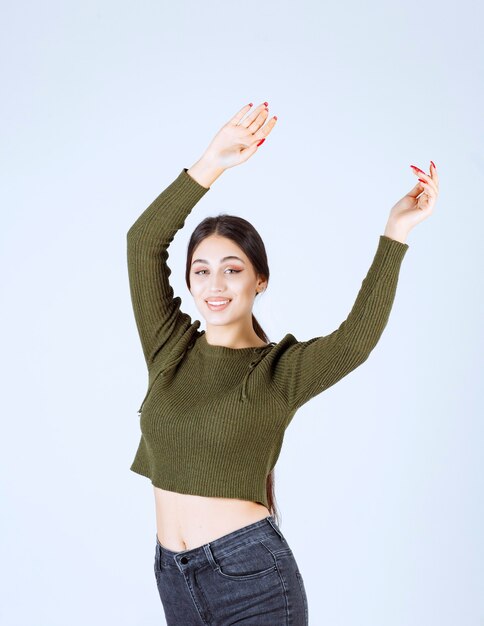 Bild eines jungen glücklichen Frauenmodells, das ihre Hände steht und anhebt.