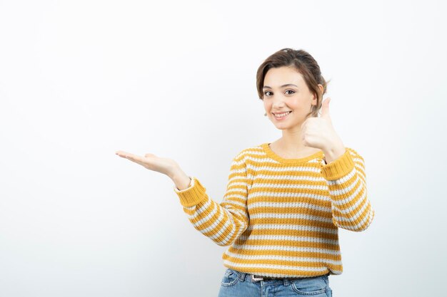 Bild eines jungen hübschen Frauenmodells, das geöffnete Handfläche und Daumen nach oben zeigt. Foto in hoher Qualität