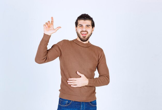 Bild eines jungen lächelnden Mannmodells, das mit einem Zeigefinger nach oben steht und zeigt. Foto in hoher Qualität