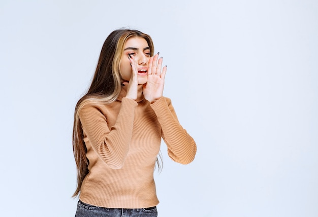 Bild eines Modells der jungen Frau in der braunen Strickjacke, die steht und aufwirft.