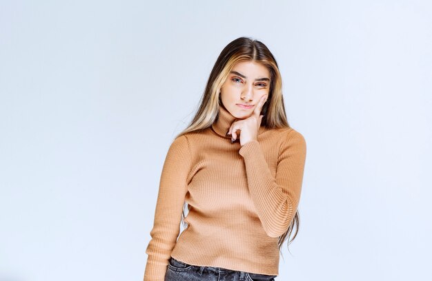 Bild eines Modells der jungen Frau in der braunen Strickjacke, die steht und aufwirft.