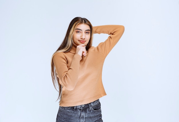 Bild eines Modells der jungen Frau in der braunen Strickjacke, die steht und aufwirft.