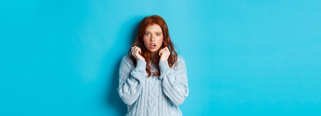 Kostenloses Foto bild eines verängstigten teenagermädchens mit roten haaren, das erschrocken springt und alarmiert aussieht, während es über blauem b steht