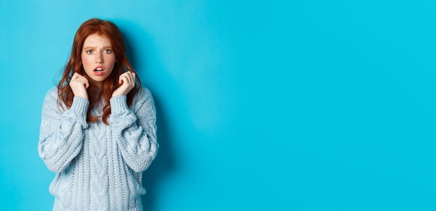 Kostenloses Foto bild eines verängstigten teenagermädchens mit roten haaren, das erschrocken springt und alarmiert aussieht, während es über blauem b steht