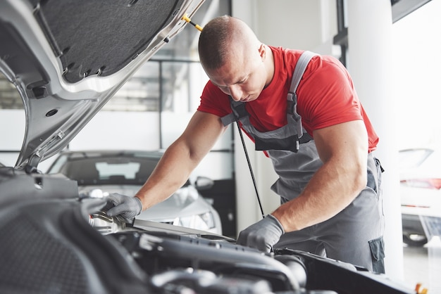 Bild zeigt muskulösen Autoservice-Arbeiter, der Fahrzeug repariert.