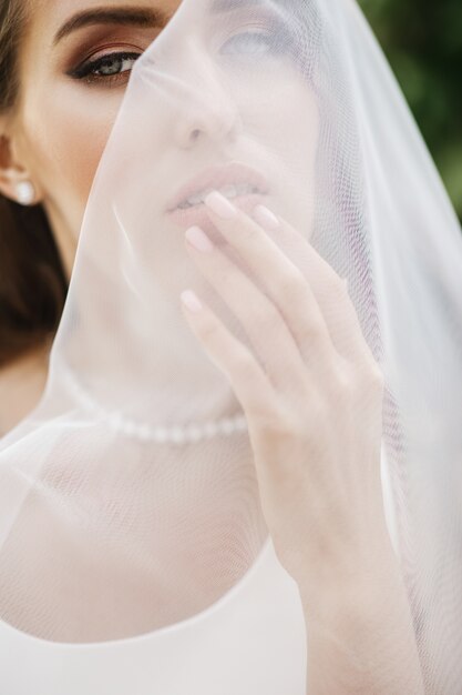 Bilder der erstaunlichen Braut draußen aufwerfend unter dem Schleier