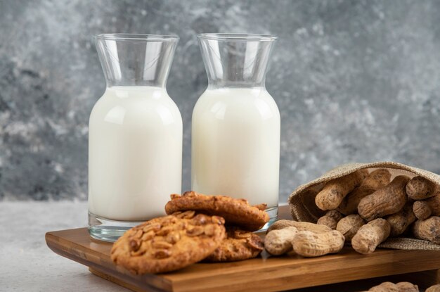 Bio-Erdnüsse, frische Milch und leckere Kekse auf Marmortisch.