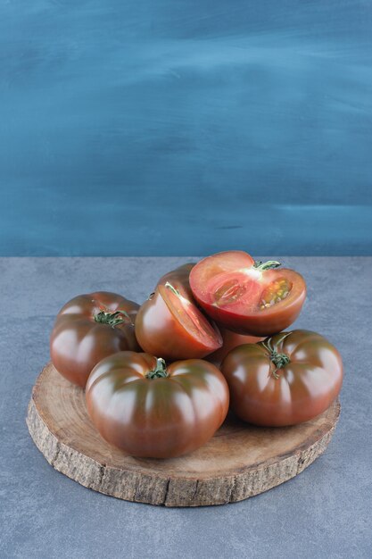 Bio frische ganze und geschnittene Tomaten auf Holzstück.