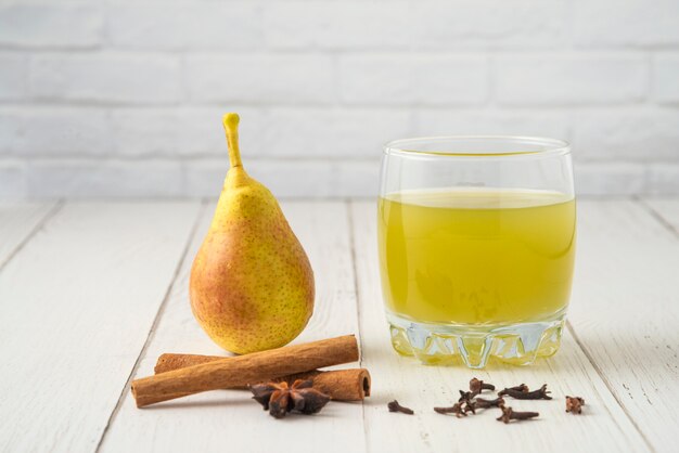 Birne und Saft in Glasbechern auf dem Holztisch