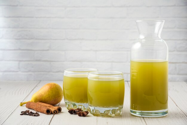 Birne und Saft in Glasbechern auf dem Holztisch