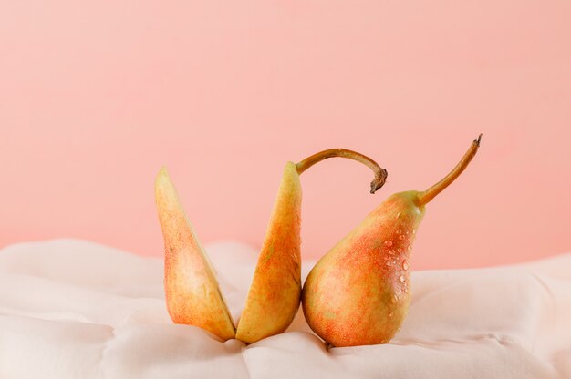 Birnen auf rosa und textiler Oberfläche