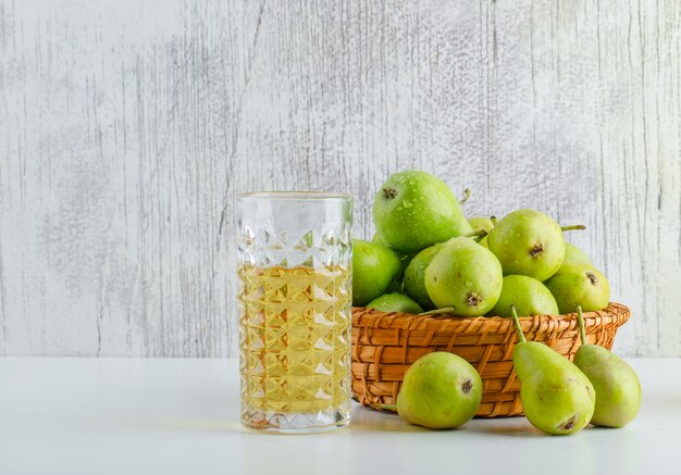 Birnen mit Getränk in einem Korb auf weißem und schmuddeligem Hintergrund, Seitenansicht.