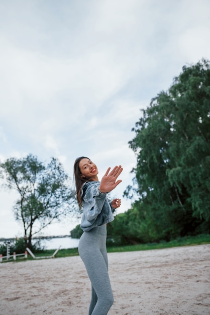 Bis bald. positive frau in sportlicher kleidung, die natur am strand genießt