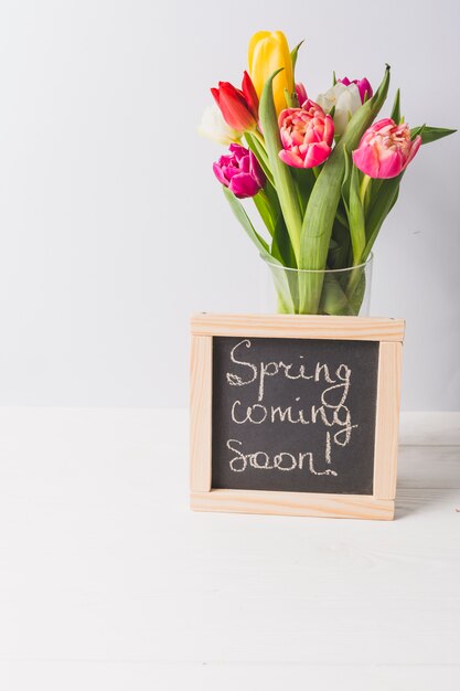 Blackboard in der Nähe von Vase mit Tulpen