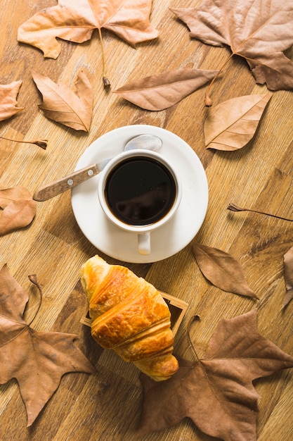 Kostenloses Foto blätter um kaffee und croissant
