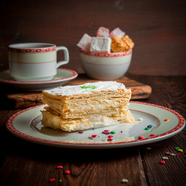 Kostenloses Foto blätterteigkuchen mit tasse tee und zucker in rundem teller