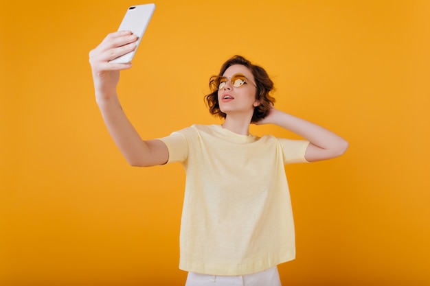Blasses Mädchen mit dem Fotografieren von sich selbst im gelben Raum