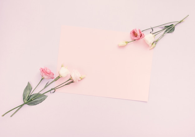 Blatt des leeren Papiers mit hellen Blumen auf Tabelle