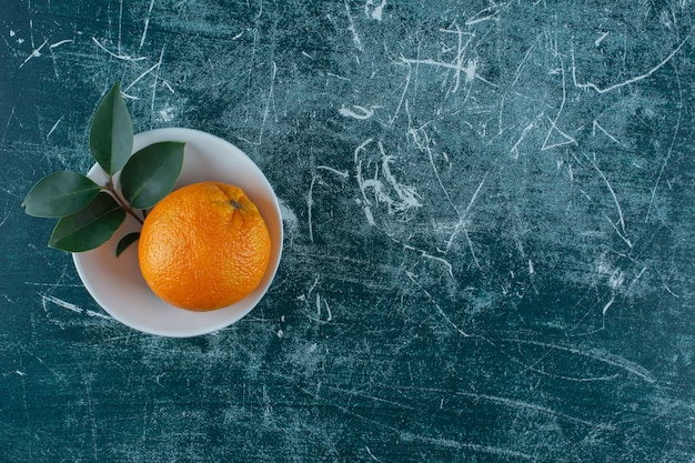 Blatt und Mandarine in Schüssel auf dem Marmortisch.