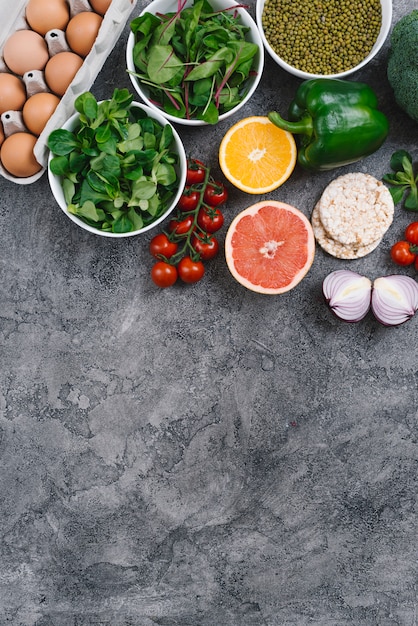 Kostenloses Foto blattgemüse; zitrusfrucht; eier; puffreiskuchen und mungobohne auf konkretem hintergrund