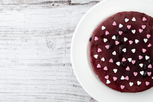 Blaubeerkäsekuchen verziert mit süßen Herzen auf Holztisch