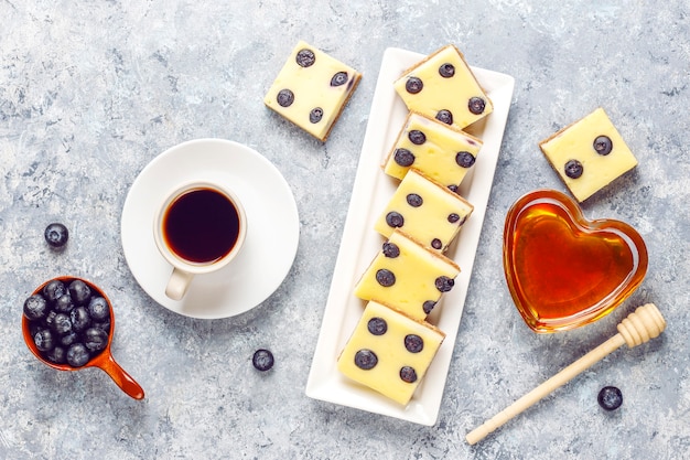 Blaubeerkäsekuchenriegel mit Honig und frischen Beeren.