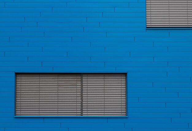 Blaue Backsteinmauer mit grauen Fensterblenden