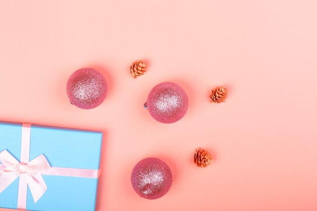 Blaue glitzer-geschenkbox mit band und weihnachtsspielzeug auf rosa hintergrund. minimalistischer weihnachtshintergrund mit leerem platz für text