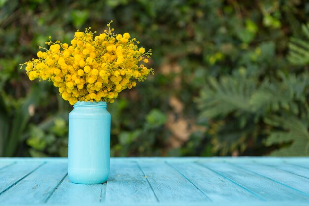Blaue hölzerne Oberfläche mit Blumen auf einer Vase