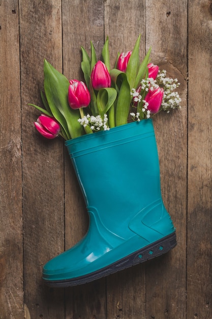 Blaue Kunststoff-Stiefel mit Blumen auf Holztisch