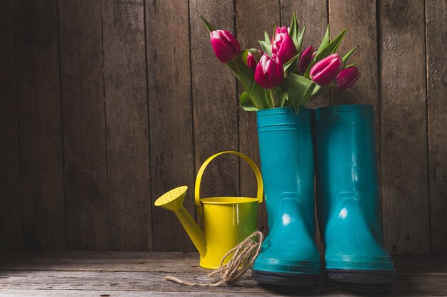 Blaue Kunststoff-Stiefel mit Blumen und Gießkanne