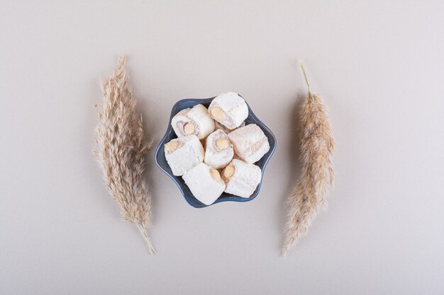 Blaue Schüssel süße Desserts mit Nüssen auf weißem Hintergrund. Foto in hoher Qualität