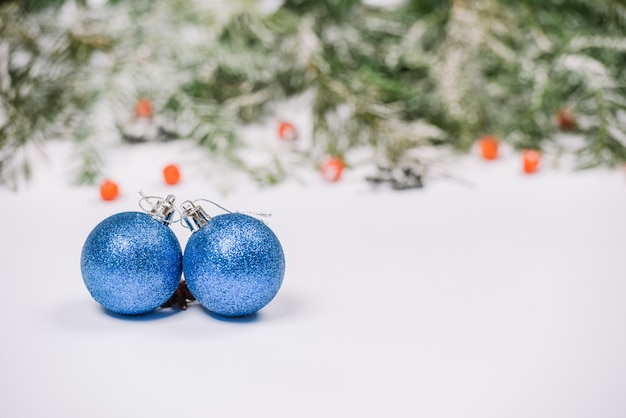 Blaue Weihnachtskugeln auf Schnee mit Tannenzweigen