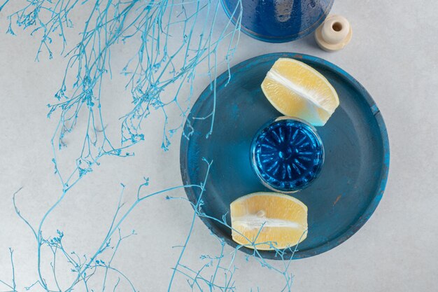 Blauer Cocktail mit Zitronenscheiben auf blauem Teller