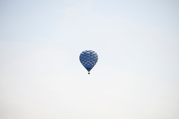 Blauer Heißluftballon fliegt in den Himmel