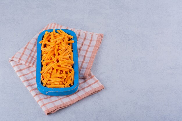 Blauer Teller mit knusprigen Kartoffelchips auf Stein.