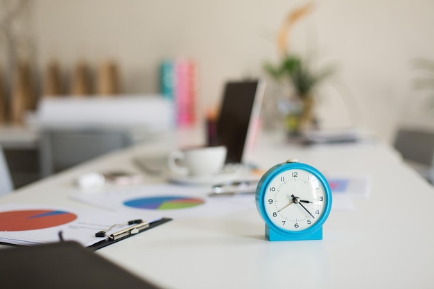 Blauer Wecker auf dem Schreibtisch im modernen Büro hautnah