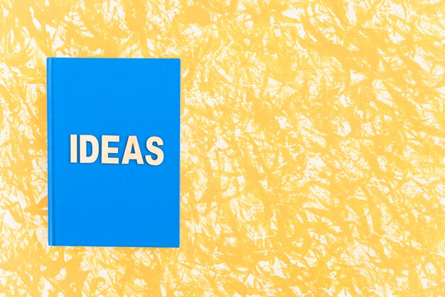 Blaues Abdeckungsbuch der Ideen auf gelbem Hintergrund