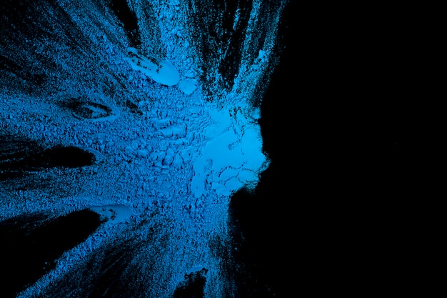 Blaues Farbenspritzen auf dunklem Hintergrund mit Kopienraum für Text