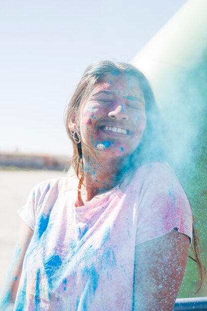 Blaues Holi-Pulver über der lächelnden jungen Frau