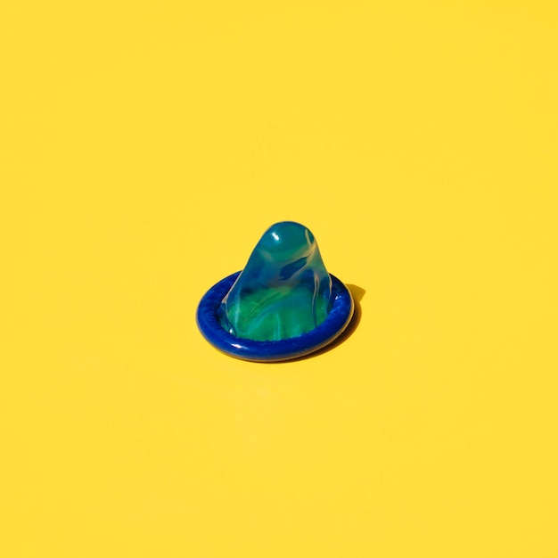 Blaues Kondom des hohen Winkels auf gelbem Hintergrund