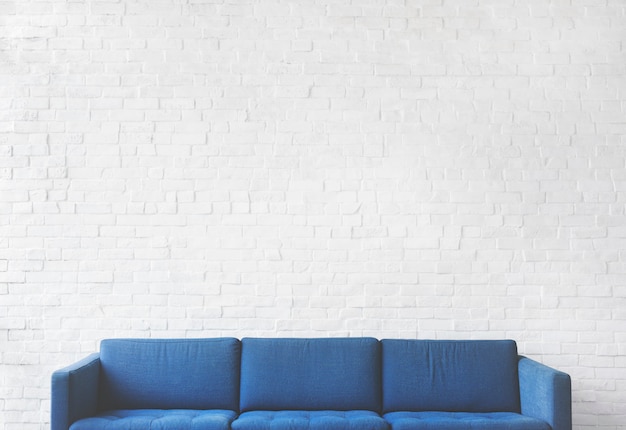 Blaues Sofa mit weißem Backsteinmauerhintergrund