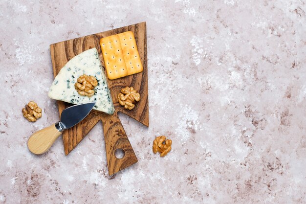 Blauschimmelkäse auf hölzernem Schneidebrett mit Honig und Walnüssen