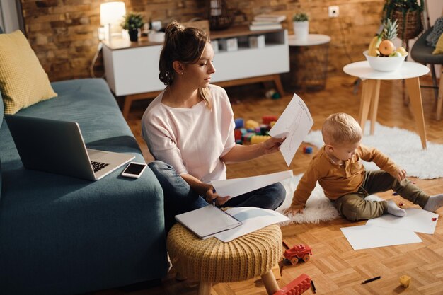 Bleiben Sie zu Hause, Mutter, die arbeitet, während sie mit ihrem Sohn im Wohnzimmer ist