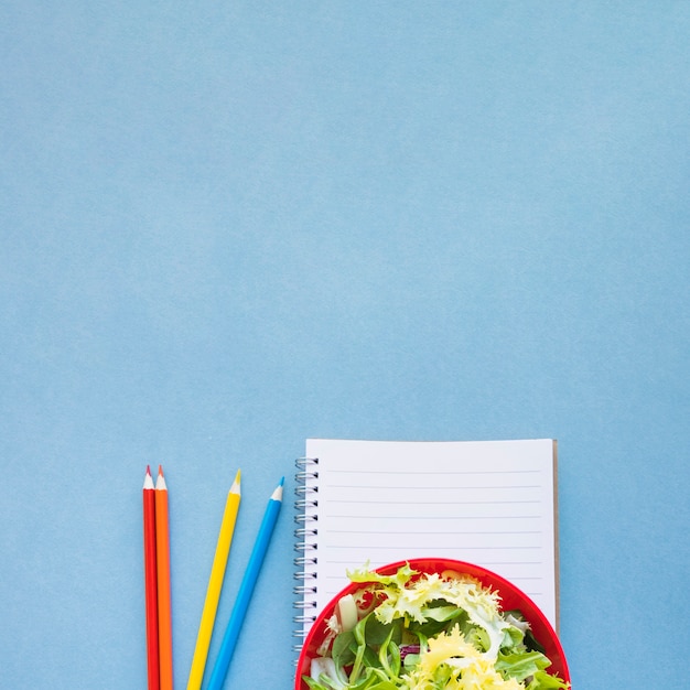 Bleistifte in der Nähe von Salat und Notebook