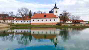 Kostenloses Foto blick auf das capriana-kloster. die steinkirche, gebäude, kahle bäume. ein see im vordergrund, gutes wetter in moldawien